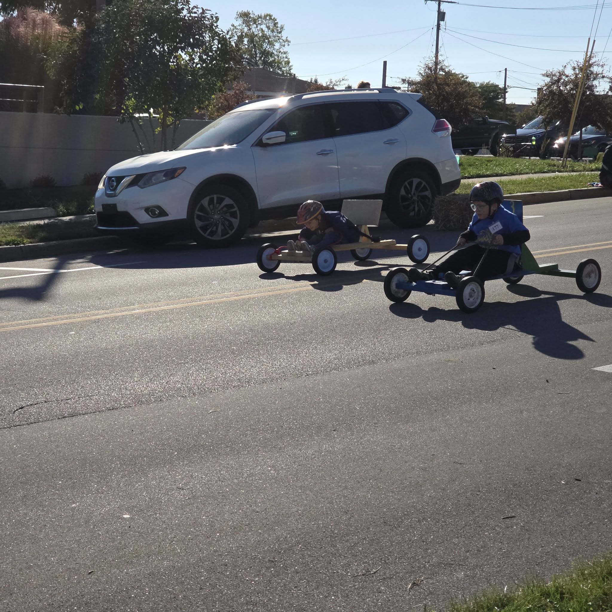 Scouts riding Cubmobiles down a hill during Pack 3726 Cubmobile Day