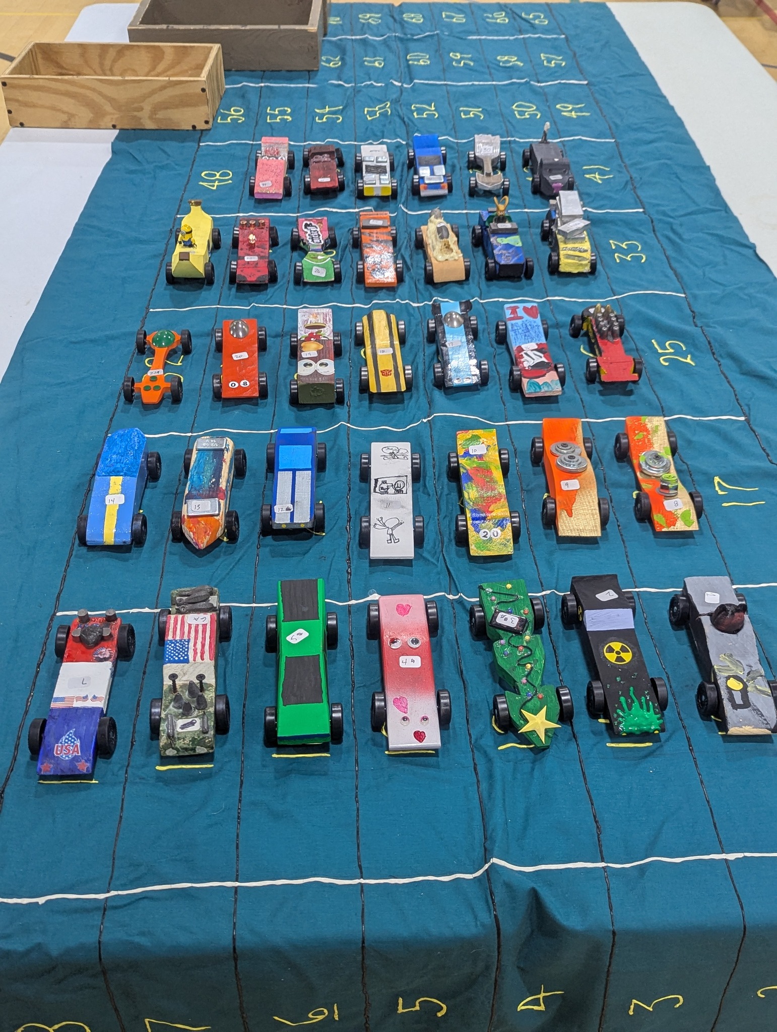 Scouts watching Pinewood Derby cars race down the track